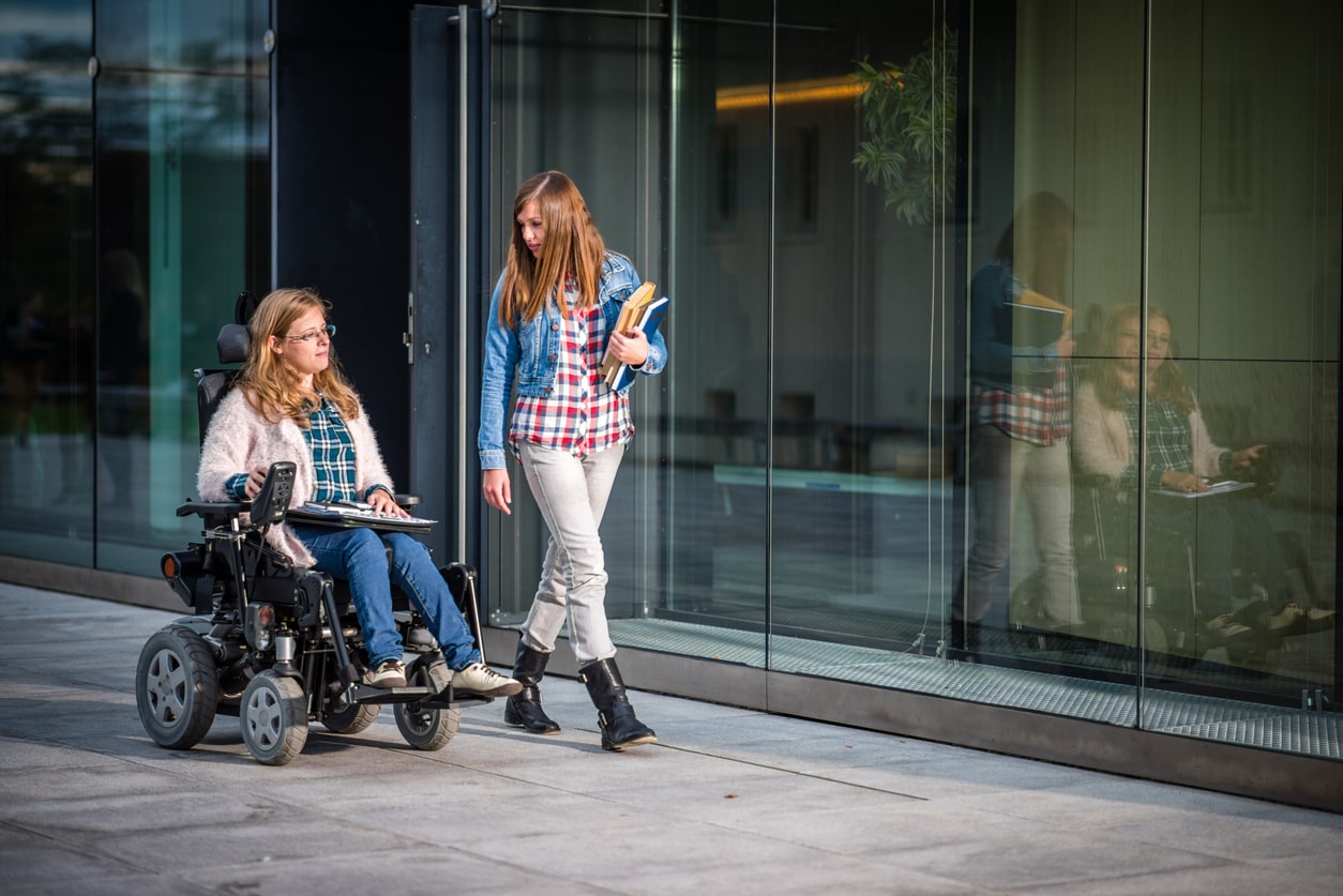 Two students go to class together, one is in a wheelchair and the other walks. Teaching students with special needs.